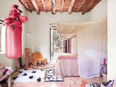 a bedroom with a bed, chair and boxing bag hanging from the ceiling in front of a window