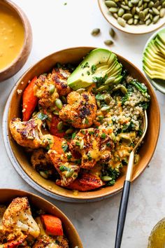 two bowls filled with different types of food next to avocado and pumpkins