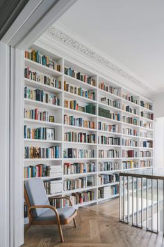 a chair sitting in front of a bookshelf filled with lots of bookcases