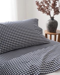 a black and white checkered sheet set on a bed with a vase full of flowers