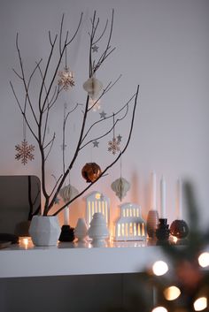 a christmas tree with lights and ornaments on it in front of a white fireplace mantel