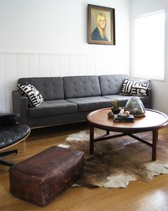 a living room filled with furniture and a cowhide rug on top of a hard wood floor