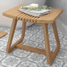 a small wooden table sitting on top of a tiled floor next to a bath tub