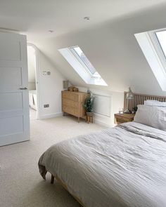 an attic bedroom with white walls and carpeted flooring, two skylights above the bed