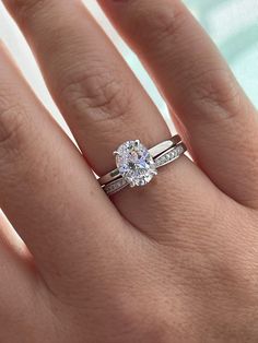 a woman's hand with a diamond ring on top of her finger and the other hand holding an engagement ring