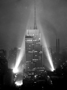 the empire building in new york city at night with beams of light coming from it