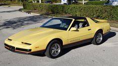 a yellow sports car is parked on the side of the road in front of some bushes