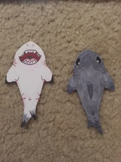 two pieces of paper cut to look like shark and dolphin with mouths open on the floor