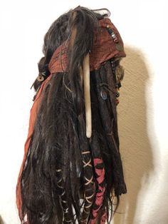 a wig with long hair and horns hanging on a wall next to a white wall