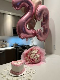 a cake and balloons on a table in a kitchen with the number twenty two spelled out