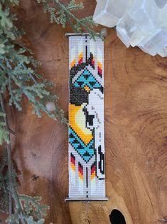 a beaded bracelet with an image of a bird on it sitting on top of a piece of wood