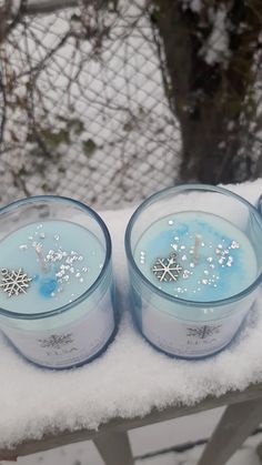 three blue candles sitting on top of snow covered ground