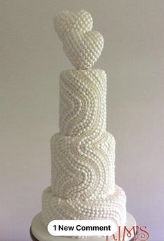 a three tiered white wedding cake decorated with beads