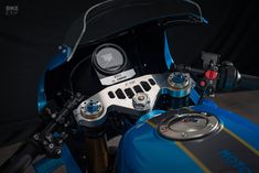 a close up view of the handlebars on a blue and gold motorcycle with black background