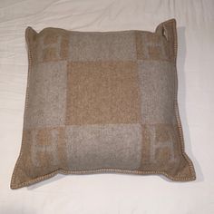 a brown and tan pillow sitting on top of a white bed covered in sheets with checkered design