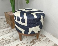 a blue and white ottoman sitting on top of a wooden floor next to a potted plant