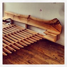 a wooden bed frame sitting on top of a hard wood floor next to a wall