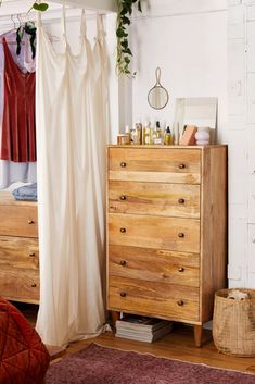 a bedroom with a dresser, bed and hanging plants on the wall next to it