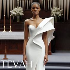 a woman standing in front of a church organ wearing a white dress with an asymmetrical neckline