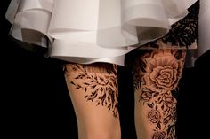 a woman's legs with black and white tattoos on them, all covered in flowers