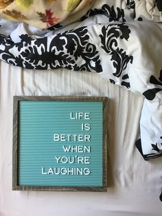 a sign that says life is better when you're laughing on the side of a bed