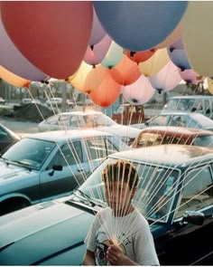 a man is holding balloons in front of his face