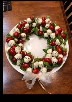 a wreath made out of tomatoes and mozzarella on a white plate with ribbon