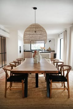 a dining room table with chairs and a vase on top of it in front of a window