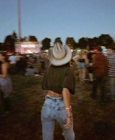 a person with a cowboy hat on their head in the middle of a field at night