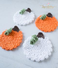 four crocheted pumpkin coasters sitting on top of a table