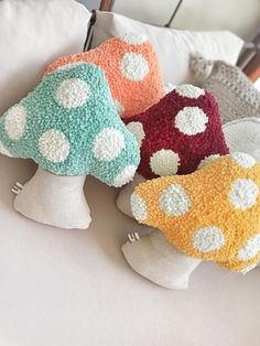 four crocheted mushrooms sitting on top of a white couch next to each other