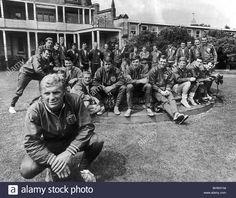 a group of men sitting on top of a lush green field next to a building