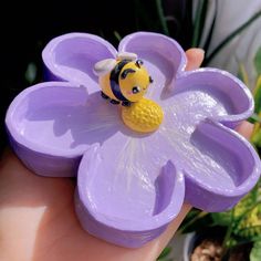 a toy bee sitting on top of a purple flower