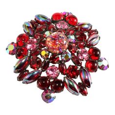 This is part of Chairish’s Costume Jewelry assortment.  Large vintage brooch comprised of red and pink rhinestones and cabochons in various shapes and sizes. The central stone is a foiled cabochon "cat's eye" stone. Setting is dark silver in color. We believe this piece dates to the early 1960s. Unmarked. Measures about 2 5/8" inches across. This captivating brooch is in excellent vintage condition showing some wear to the plating on the back. Vintage Red Brooches For Party, Red Costume Jewelry Brooch, Antique Red Brooches For Gift, Antique Red Brooches As Gift, Antique Red Brooch Jewelry, Antique Costume Jewelry, Cats Eye Stone, Eye Stone, Stone Setting