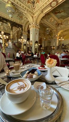 there is a cup of coffee on the table with other plates and cups in front of it