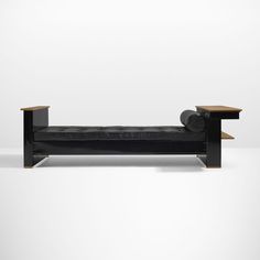 a black leather couch sitting on top of a wooden table next to a white wall