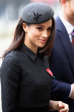 the woman is wearing a hat with a rose on it and she is looking at the camera