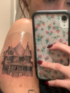 a woman is holding up her phone case to show the tattoo on her arm