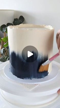 someone is decorating a cake with blue and white icing on the top layer