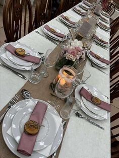 the table is set with plates, silverware and pink napkins for an elegant dinner