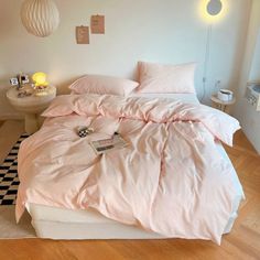 a bed with pink comforter and pillows in a white room next to a checkered rug