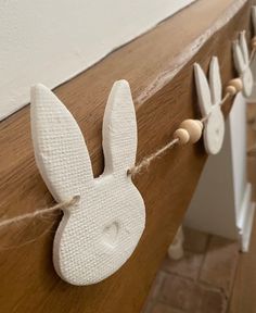 some white bunny ears are hanging on the side of a wooden board with string attached to it