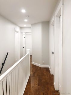 an empty hallway with wooden floors and white walls