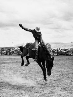 a black and white photo of a man riding a horse in the middle of nowhere