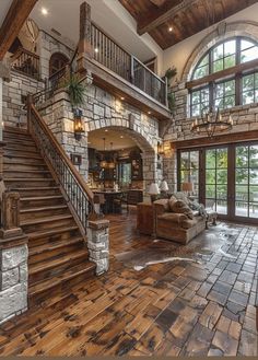 a large living room with wood floors and stone walls, along with two staircases that lead up to the second floor