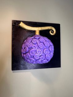 a purple object is hanging on the wall next to a black plaque with a gold handle