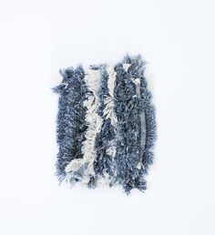 a pile of blue and white rugs sitting on top of a white floor next to a wall