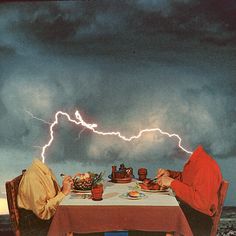 two people sitting at a table with food and lightning in the sky above their heads