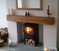 a wood burning stove in a living room next to a mirror and firewood logs