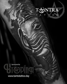 an arm with a black and white tattoo on it, depicting the face of buddha